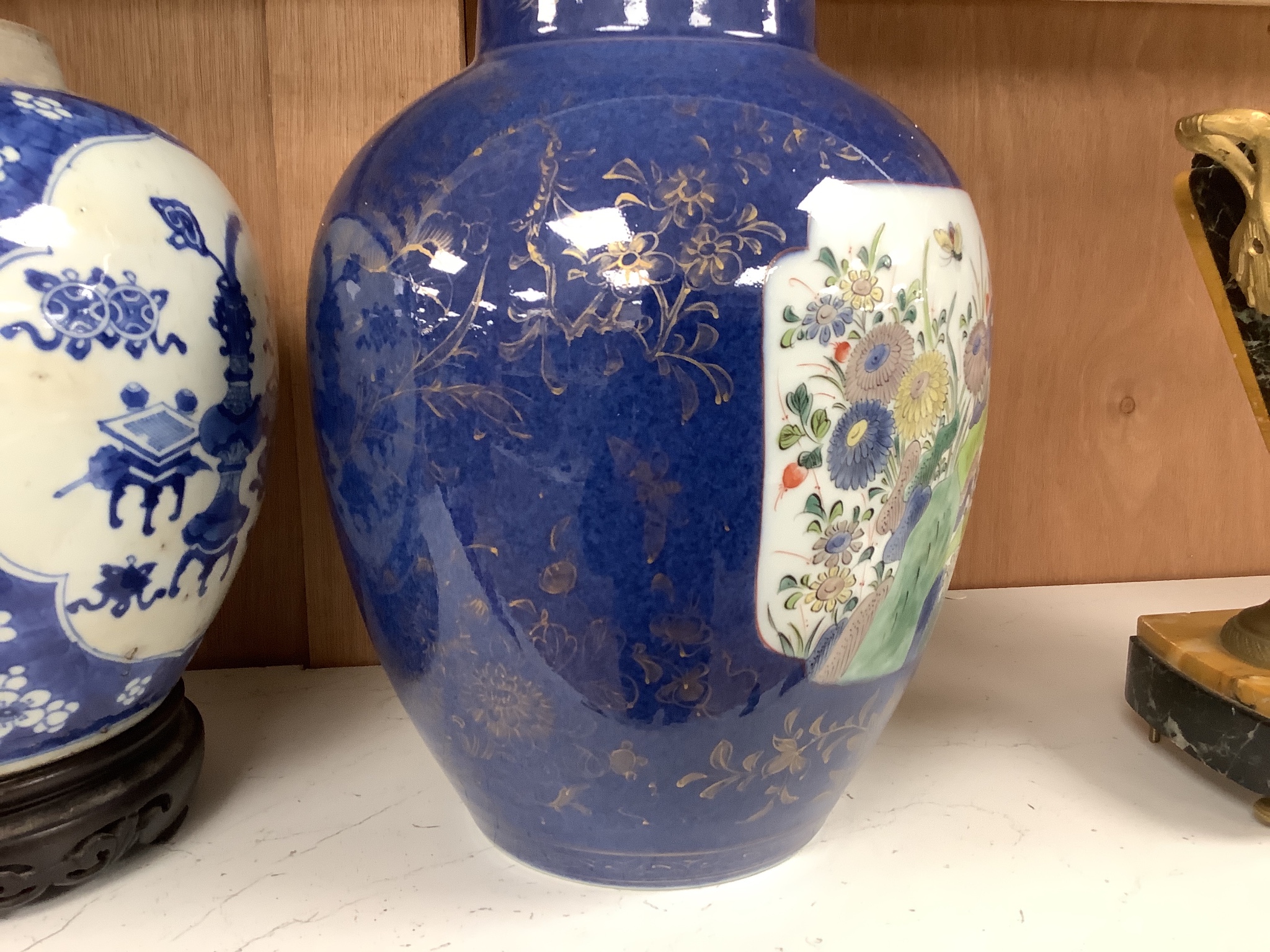 A Chinese Kangxi blue and white hundred antiques jar, 21cm, cracked, with hardwood stand and a Samson powder blue jar, 26cm, wear